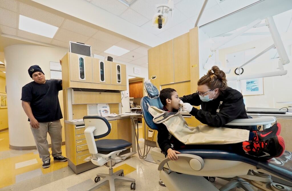 Odontologa atendiendo a un paciente en el sillon dental de una clinica moderna